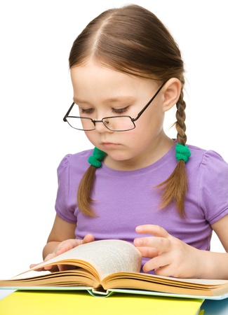 Cute little girl reading book wearing glasses, isolated over whiteの写真素材