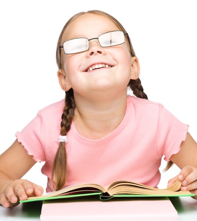 Cute little schoolgirl with a book wearing glasses, isolated over whiteの写真素材