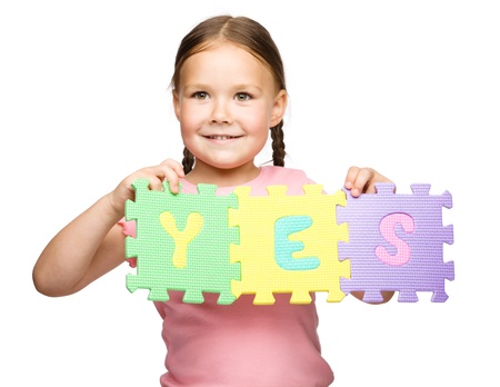 Cute little girl is holding Yes slogan, isolated over whiteの写真素材