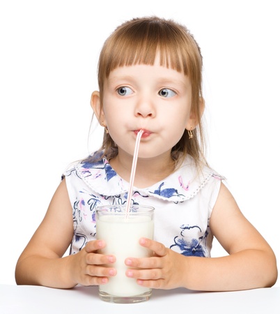 Cute little girl drinks milk using drinking straw, isolated over whiteの写真素材