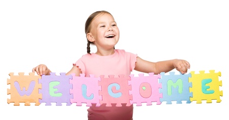 Cute little girl is holding Welcome slogan, isolated over whiteの写真素材