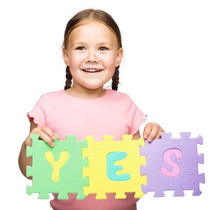 Cute little girl is holding Yes slogan, isolated over whiteの写真素材