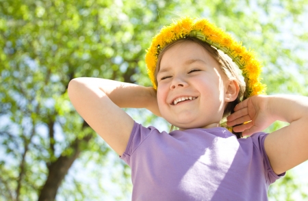 Outdoor portrait of a cute little girl with dandelion wreathの写真素材