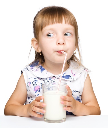 Cute little girl drinks milk using drinking straw, isolated over whiteの写真素材