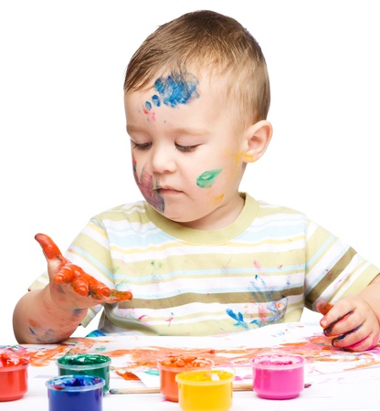 Portrait of a cute little boy messily playing with paints, isolated over whiteの写真素材