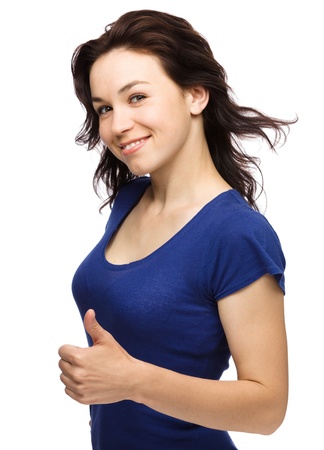 Young woman dressed in blue is showing thumb up gesture, isolated over whiteの写真素材