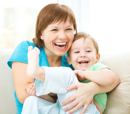 Mother and her son is having fun while sitting on a couchの写真素材