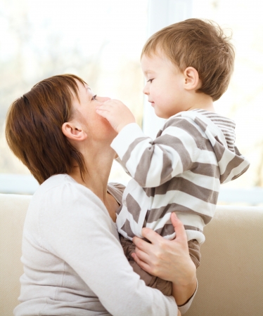 Mother holding her son while sitting on a couchの写真素材