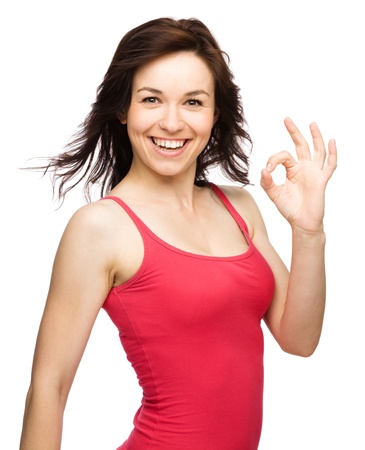 Young woman dressed in red showing OK sign, isolated over whiteの写真素材