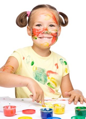 Portrait of a cute cheerful girl playing with paints, isolated over whiteの写真素材