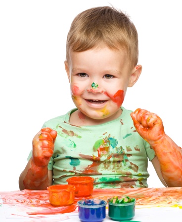 Portrait of a cute little boy playing with paints clenching his fists in joy, isolated over whiteの写真素材