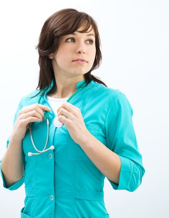 Portrait of a young attractive woman wearing doctor uniform and glasses, isolated over whiteの写真素材