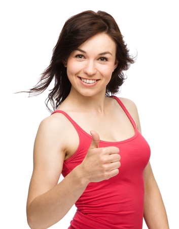 Young woman dressed in red is showing thumb up gesture, isolated over whiteの写真素材