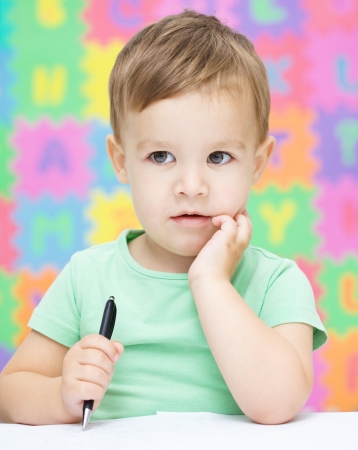 Little boy is writing on his copybook in preschoolの写真素材