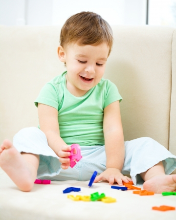 Cute little boy is playing while sitting on couchの写真素材