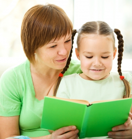 Mother is reading book with her daughter, indoor shootの写真素材