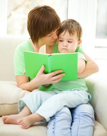 Mother is reading book for her son, indoor shootの写真素材