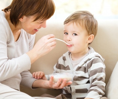 Cute little boy is fed using spoon, indoor shootの写真素材