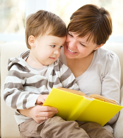 Mother is reading book for her son, indoor shootの写真素材