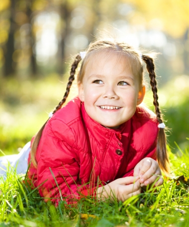 Portrait of a cute little girl in autumn parkの写真素材