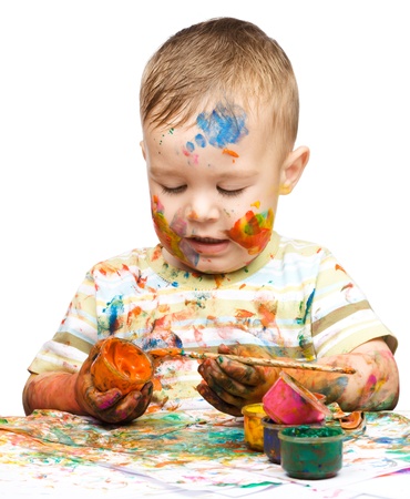 Portrait of a cute little boy playing with paints, isolated over whiteの写真素材