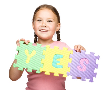 Cute little girl is holding Yes slogan, isolated over whiteの写真素材