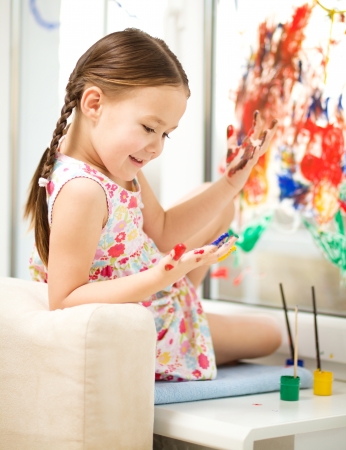 Portrait of a cute cheerful girl playing with paints on windowの写真素材