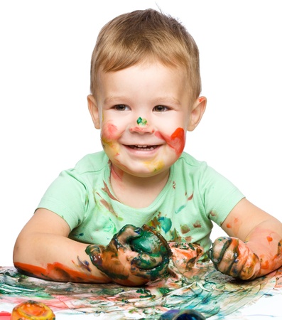 Portrait of a cute little boy playing with paints, isolated over whiteの写真素材