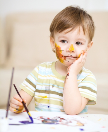 Portrait of a cute little boy messily playing with paintsの写真素材