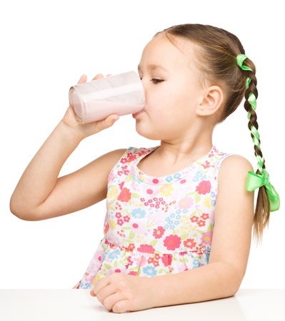 Cute little girl drinks milk, isolated over whiteの写真素材