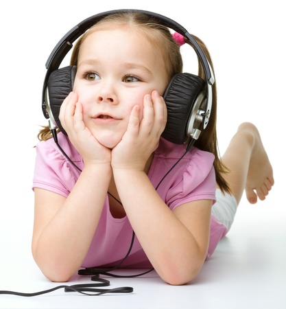 Cute little girl enjoying music using headphones, isolated over whiteの写真素材