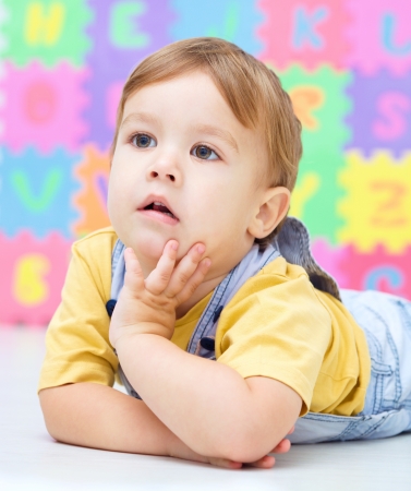 Portrait of a little boy laying on floorの写真素材