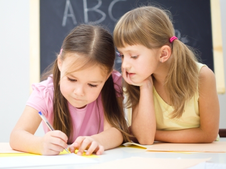 Cute little girls are writing using a pen in preschoolの写真素材