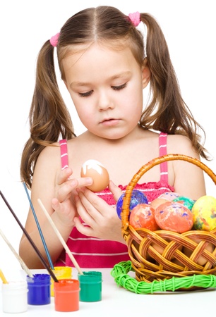 Little girl is painting eggs preparing for Easter, isolated over whiteの写真素材