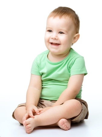 Portrait of a cute little boy sitting on floor, isolated over whiteの写真素材