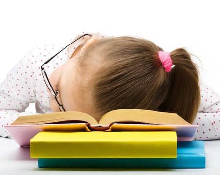 Cute little girl is sleeping on her books, isolated over whiteの写真素材