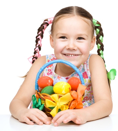 Little girl with basket full of colorful eggs preparing for Easter, isolated over whiteの写真素材