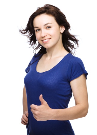 Young woman dressed in blue is showing thumb up gesture, isolated over whiteの写真素材