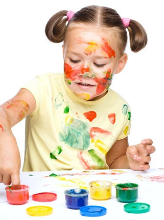 Portrait of a cute cheerful girl playing with paints, isolated over whiteの写真素材