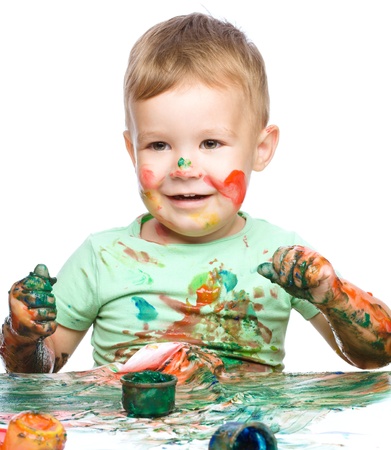 Portrait of a cute little boy playing with paints, isolated over whiteの写真素材