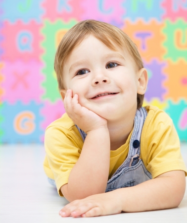 Portrait of a little boy laying on floorの写真素材