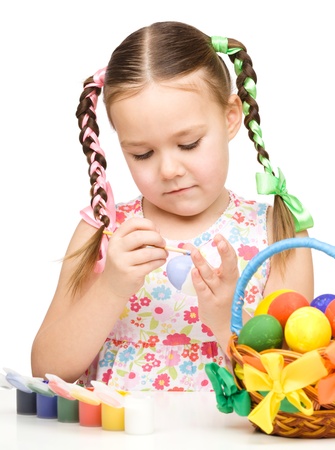 Little girl is painting eggs preparing for Easter, isolated over whiteの写真素材