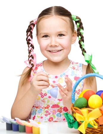 Little girl is painting eggs preparing for Easter, isolated over whiteの写真素材