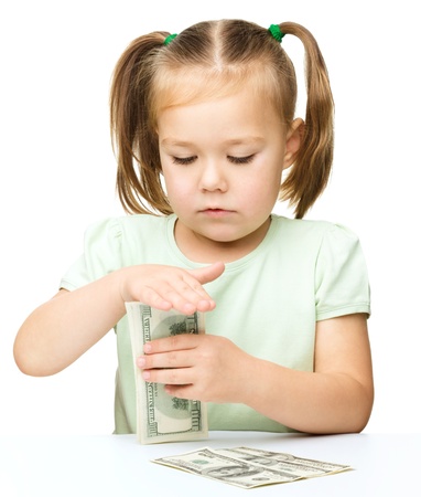 Cute little girl is counting dollars, isolated over whiteの写真素材