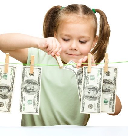 Cute little girl is playing with paper money - dollars, isolated over whiteの写真素材