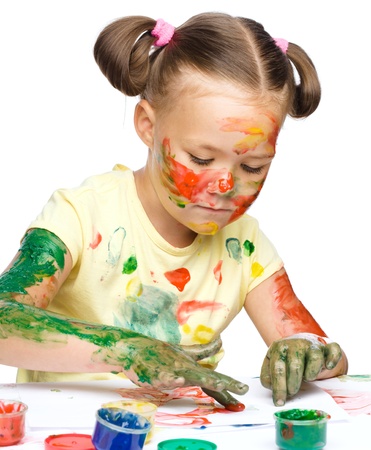 Portrait of a cute cheerful girl playing with paints, isolated over whiteの写真素材