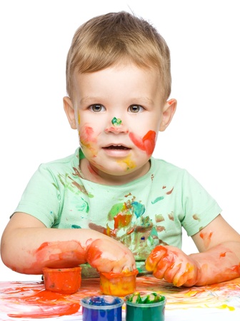 Portrait of a cute little boy playing with paints, isolated over whiteの写真素材