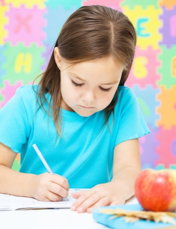 Cute little girl is writing using a penの写真素材