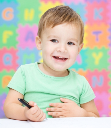 Little boy is writing on his copybook in preschoolの写真素材