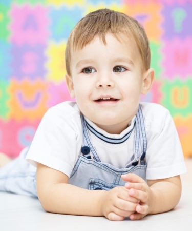 Portrait of a little boy laying on floorの写真素材
